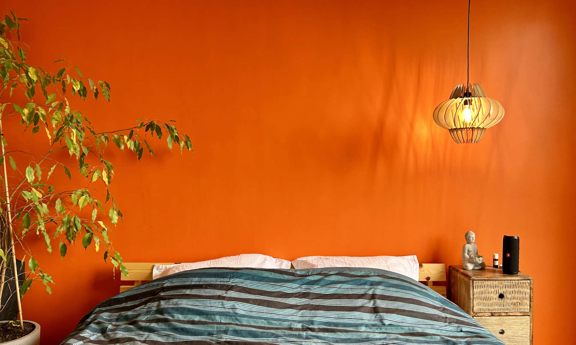 Une chambre avec un mur terracotta et un petit luminaire en bois