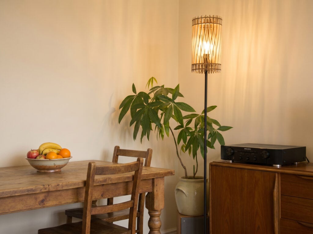 Lampadaire en bois Vincent dans un séjour lumineux, derrière une plante d'intérieur
