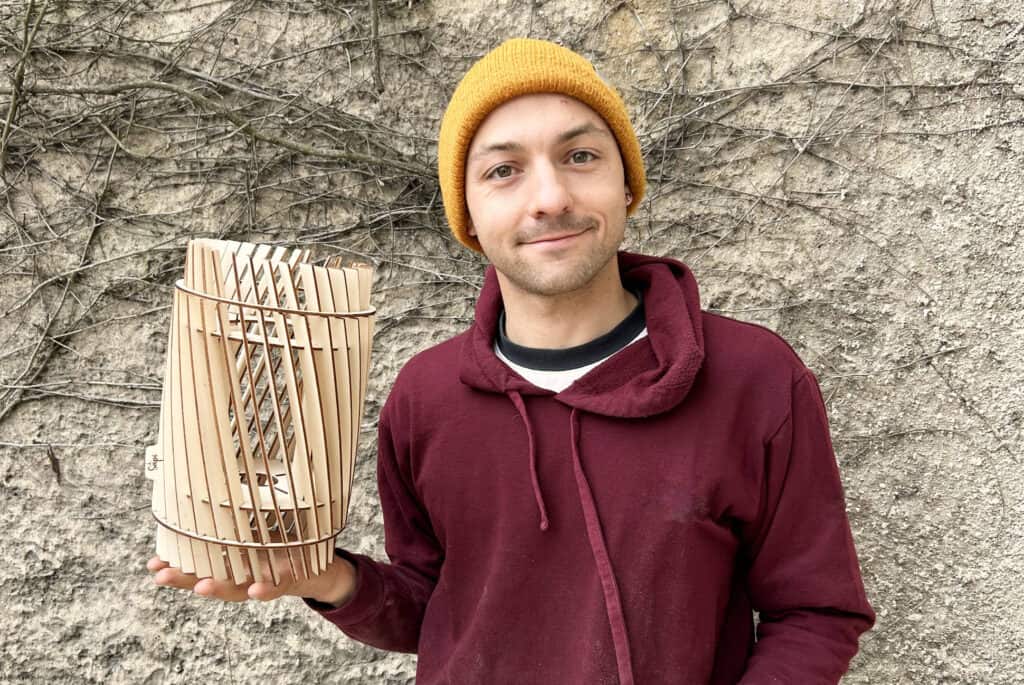 Robin, artisan à l'atelier Sâpi, avec une lampe en bois