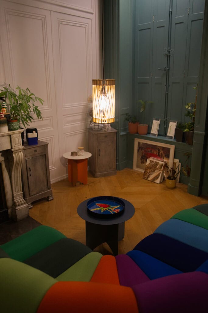 Suspension en bois découpé Atelier Sapi modèle torsadé, vue depuis le dessus dans un salon aux meubles colorés et aux portes vert-gris