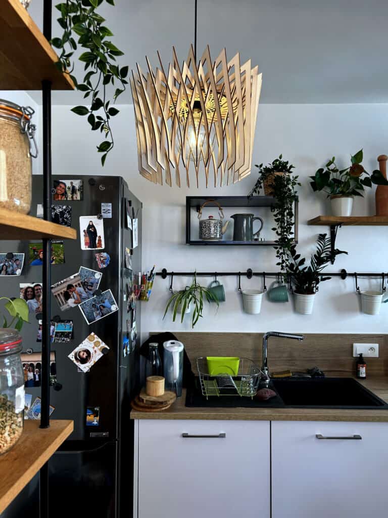 Suspension en bois découpé modèle Couronne Atelier Sapi au-dessus d'un évier de cuisine, avec plantes vertes et étagères en bois
