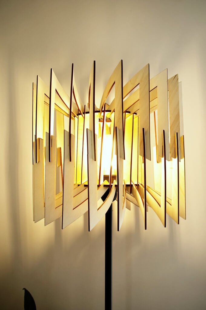 Lampadaire en bois Léon allumé, vu de face, montrant sa structure géométrique à facettes.