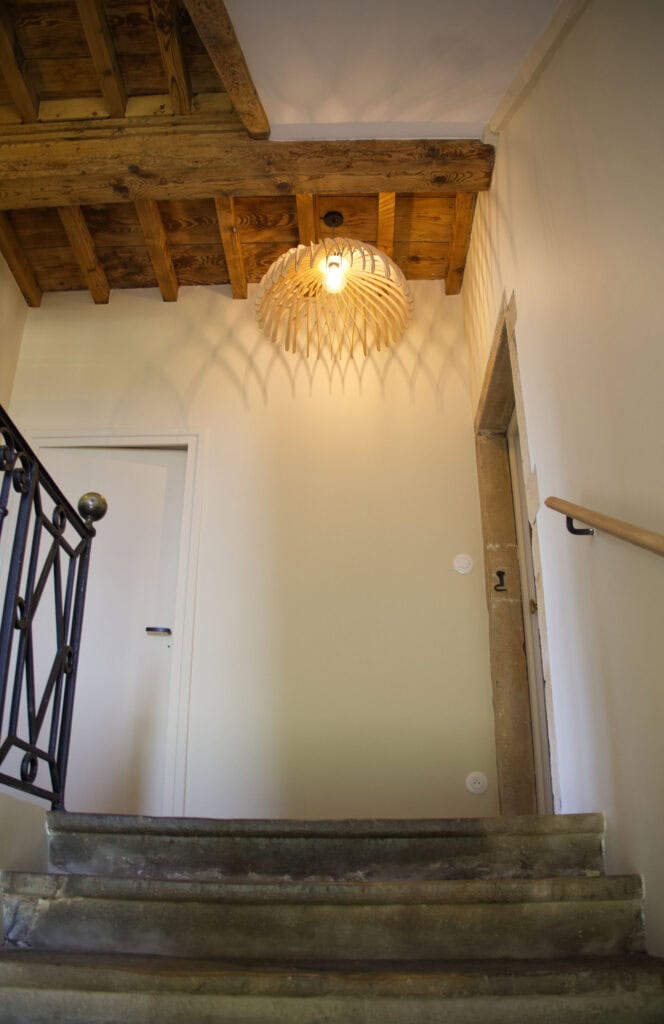 Suspension bois Suze la méduse éclairant une montée d'escalier aux murs clairs
