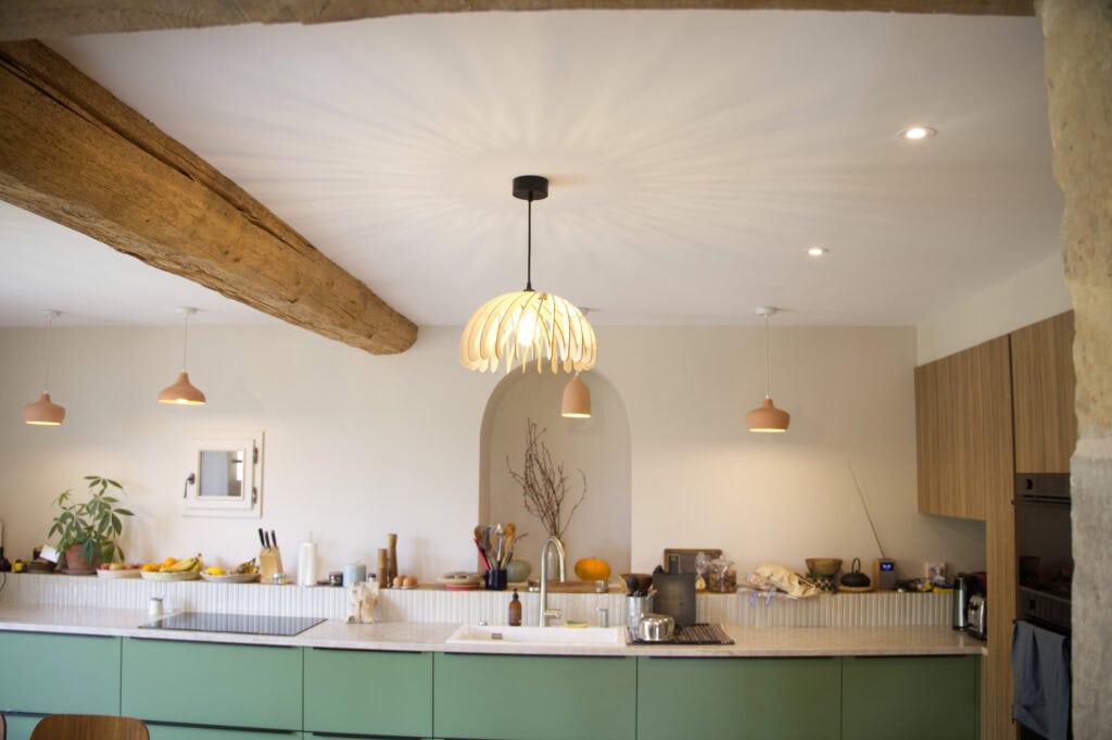Suspension bois Suze la méduse au-dessus d'un îlot dans une cuisine avec poutre apparente