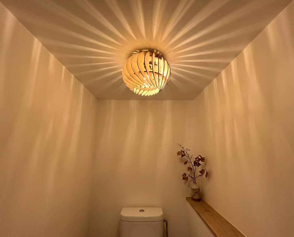 Plafonnier compact en bois Siméon le bourgeon éclairant un petit espace, un toilette.
