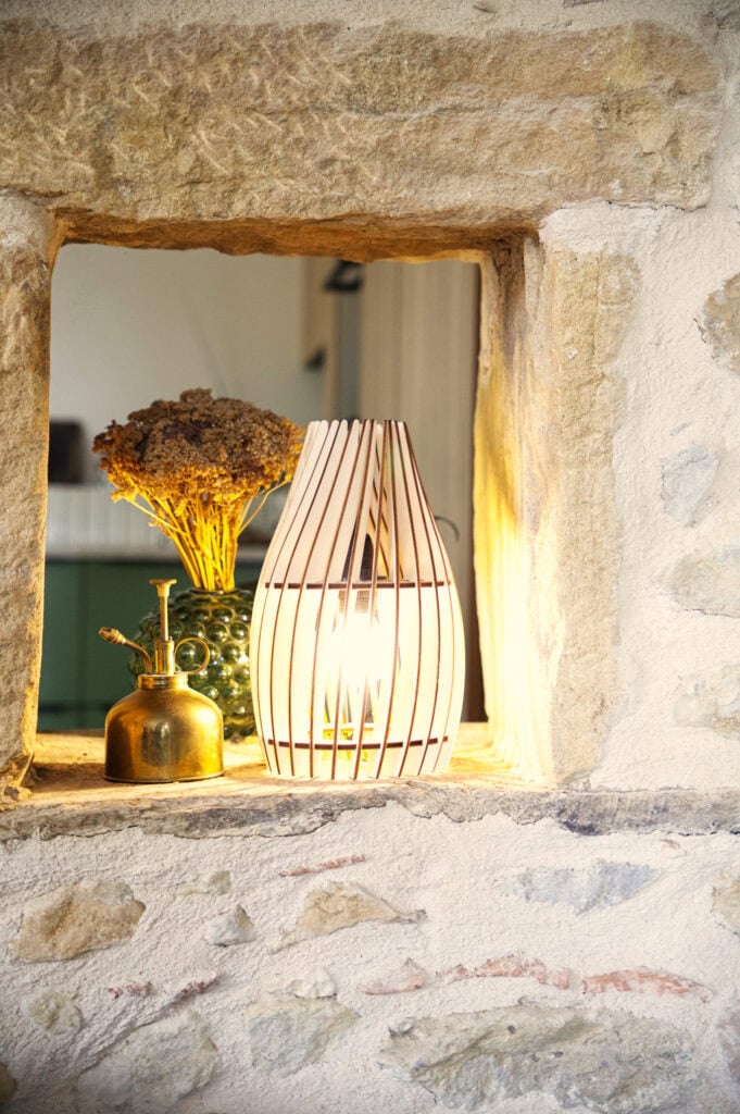 Lampe à poser en bois dans une alcôve d'un mur en pierre