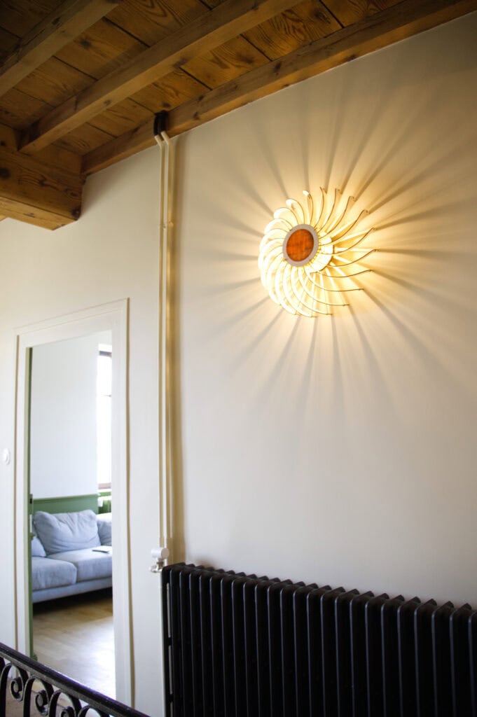 Applique murale en bois Olivia sur un mur clair, près d'une porte