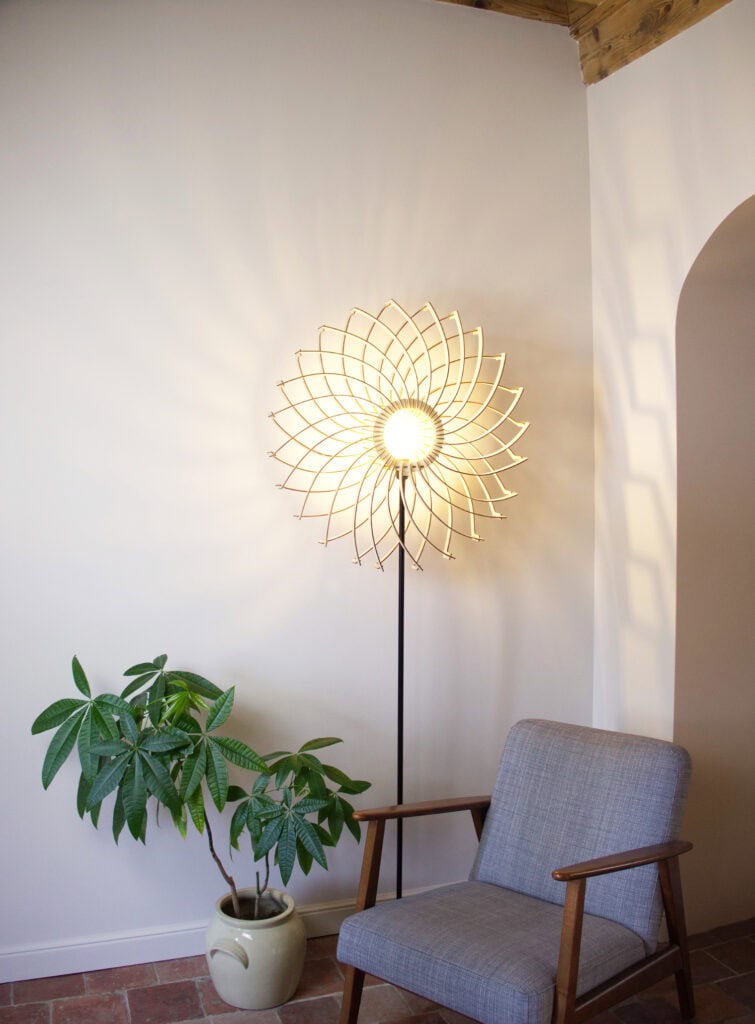Lampadaire bois Olivia dans un angle lumineux, près d'un fauteuil gris
