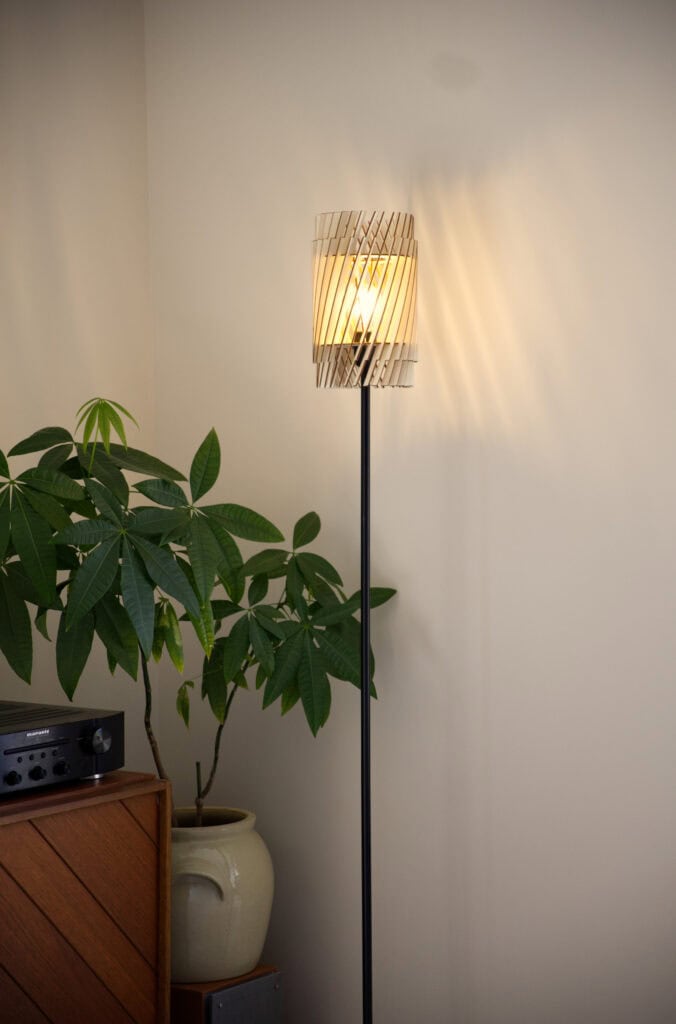 Lampadaire en bois Alice près d'une grande plante verte et d'un buffet