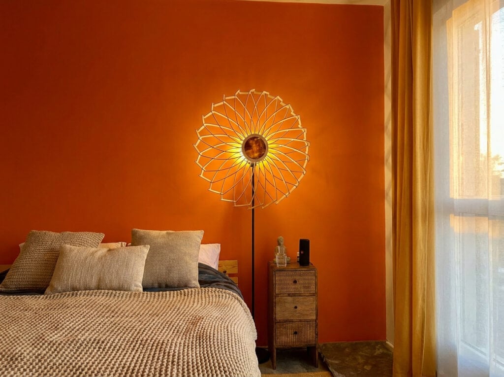 Lampadaire en bois Charlie dans une chambre terracotta aux rideaux clairs