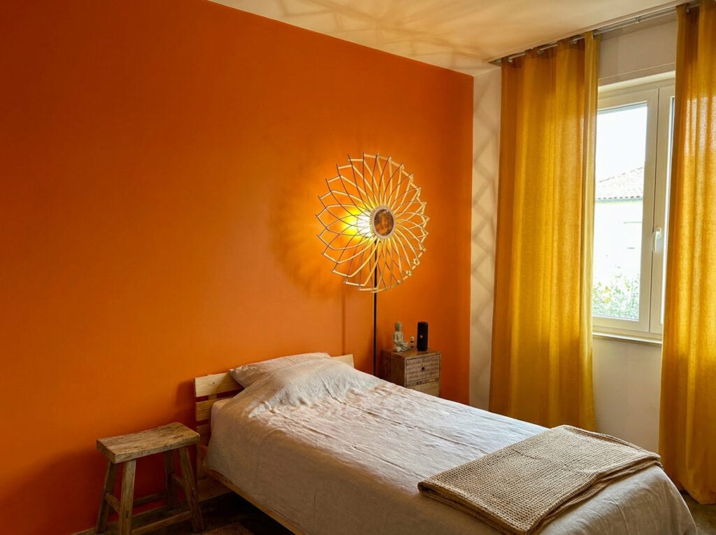 Lampadaire en bois Charlie dans une chambre au mur orange