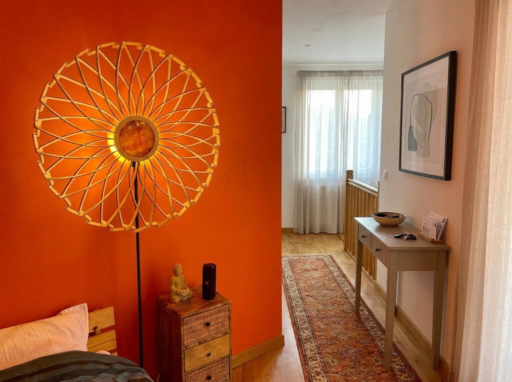 Lampadaire en bois Charlie dans une chambre orange, près d'une commode
