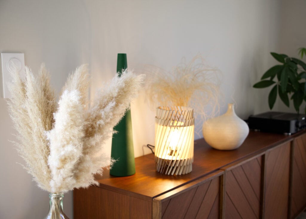 Lampe à poser en bois Alice dans un salon, sur un buffet avec bouquet de pampas