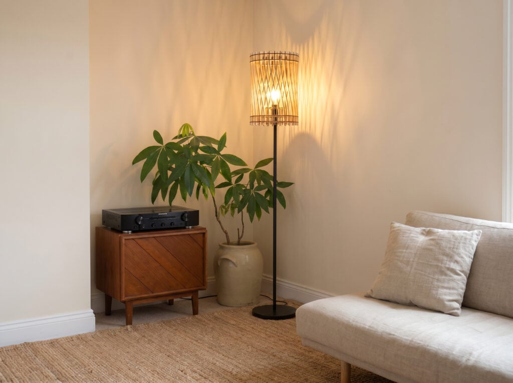 Lampadaire bois Vincent dans une pièce claire, près d'une fenêtre et d'une plante