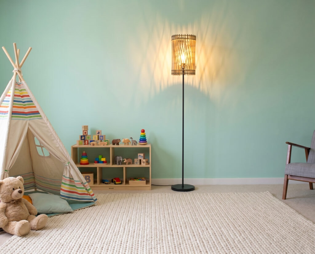 Lampadaire bois Vincent devant un mur vert d'eau, à côté d'un petit meuble, dans une chambre d'enfant