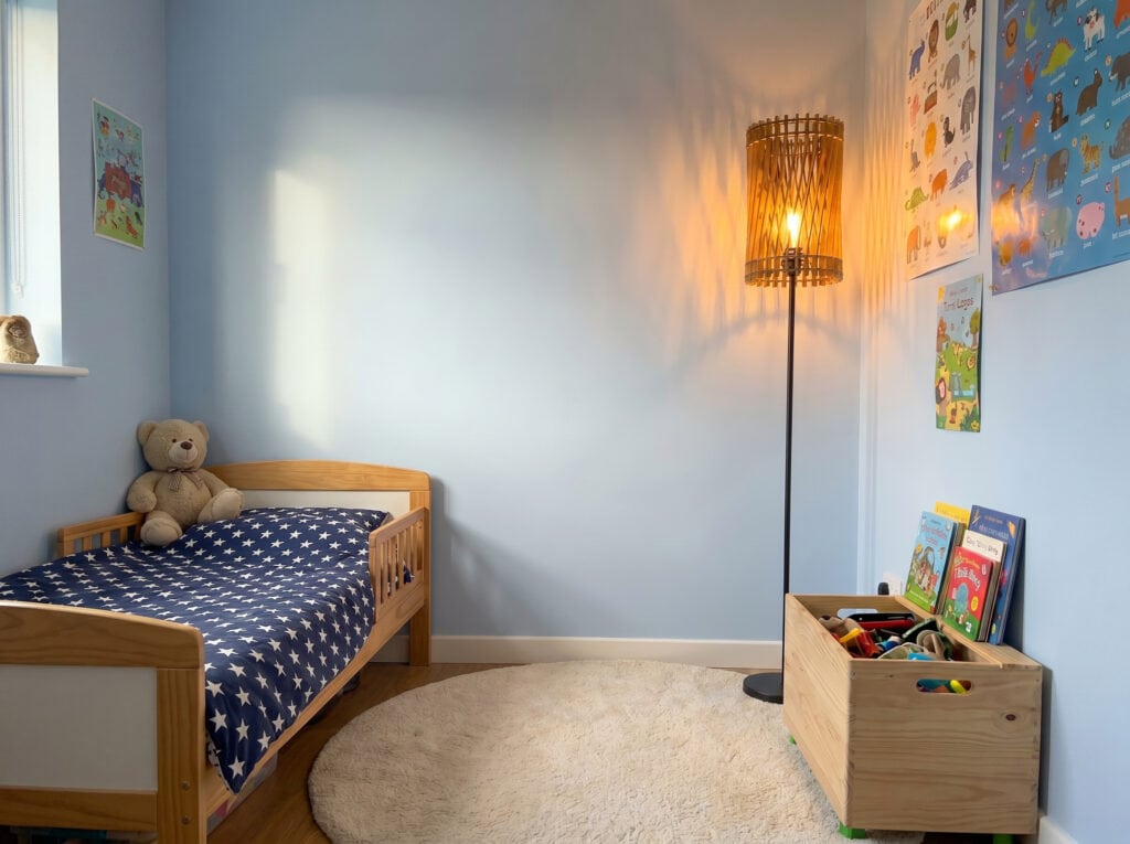 Lampadaire bois Vincent allumé dans une chambre d'enfant aux murs bleutés