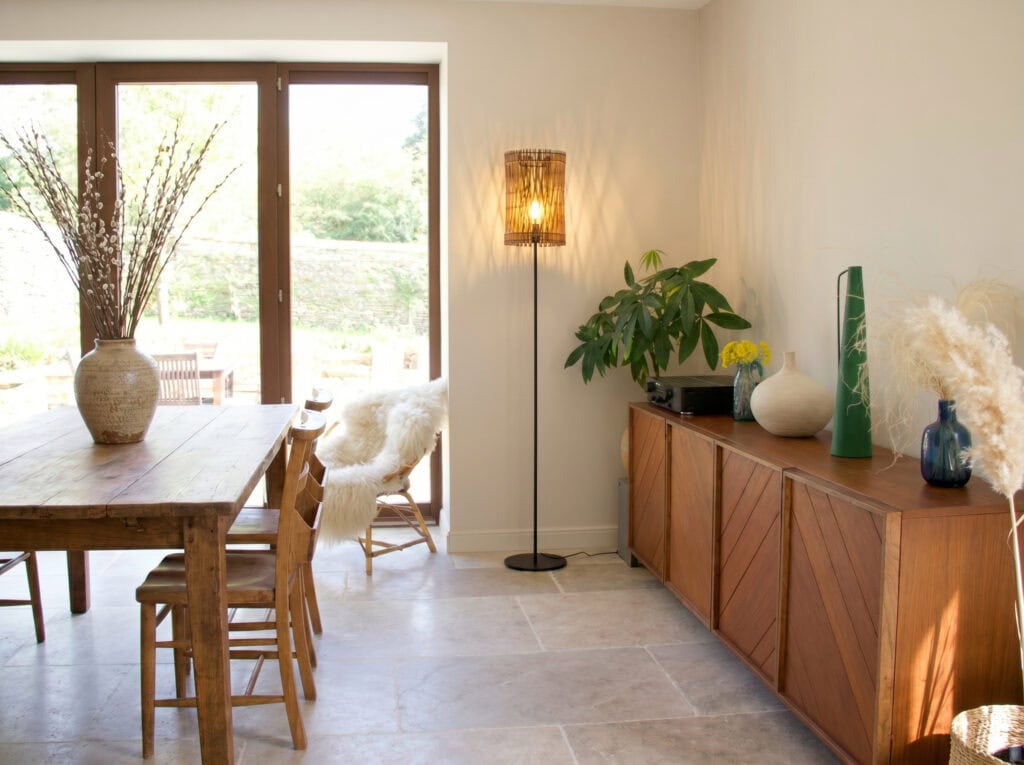 Lampadaire en bois Vincent dans une salle à manger, à côté d'un buffet en bois