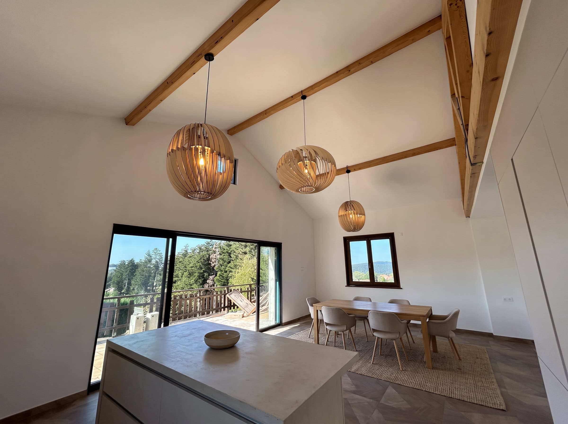 Îlot de cuisine et coin repas sous trois suspensions en bois fabriquées sur mesure par l'Atelier Sâpi